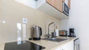 A modern kitchen with an induction cooktop, a kettle, a coffee maker, and a microwave. - Bright Valadim Apartment (Cascais)