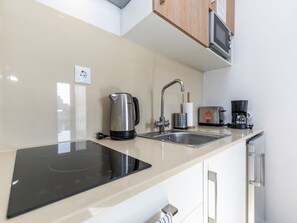 A modern kitchen with an induction cooktop, a sink, a coffee maker, and a microwave.