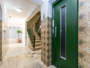 A hallway with a green door, a staircase, and a potted plant.