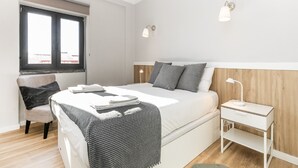 A bedroom with a bed, bedside table, lamp, chair, and a window. - Bright Valadim Apartment (Cascais)