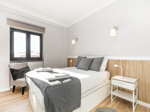 Une chambre à coucher avec un lit, des tables de chevet, une chaise et une fenêtre.