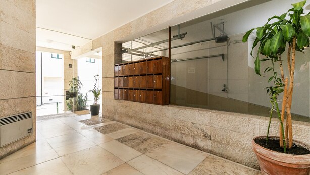 A hallway with a tiled floor, a wooden locker area, and a potted plant. - Bright Valadim Apartment (Cascais)