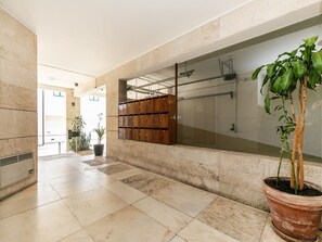 Un couloir avec un sol carrelé, un espace pour les casiers en bois et une plante en pot.