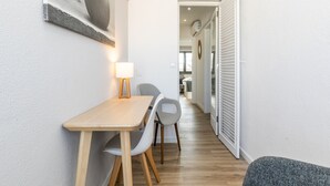 A narrow hallway with a dining area featuring a table and chairs, a wall-mounted lamp, and a door leading to another room. - Bright Valadim Apartment (Cascais)