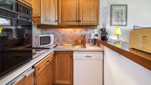Una cocina con armarios de madera, microondas, cafetera y lavavajillas.