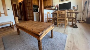 Un salón acogedor con una mesa de centro de madera, un televisor y muebles de madera.