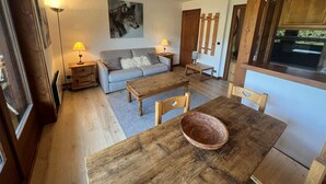Una sala de estar acogedora con un sofá, una mesa de comedor de madera y un cuadro de un lobo.