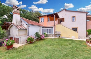 Ein Wohnhaus mit kleinem Garten, einem Ziegelkamin und einem zweistöckigen Gebäude mit Balkon.