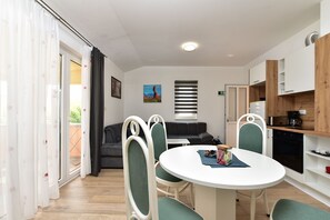 Eine moderne Küche mit Essbereich, einer Couch und Blick ins Freie.
