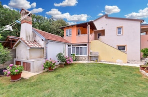 Ein Wohnhaus mit kleinem Garten, einem Ziegelkamin und einem zweistöckigen Gebäude mit Balkon.
