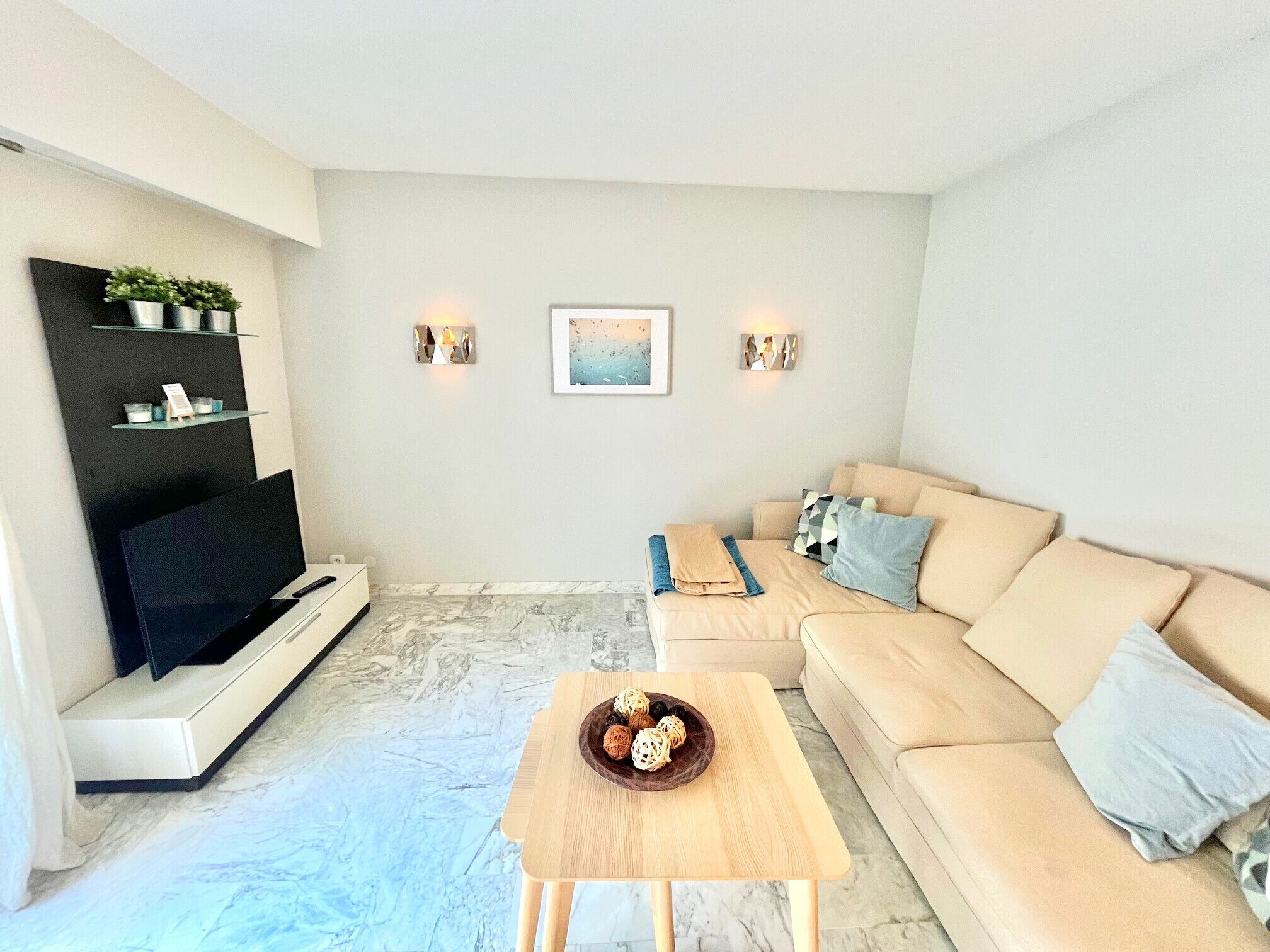 A modern living room with a beige sofa, a wooden coffee table, and a flat-screen TV.