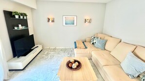 A modern living room with a beige sofa, a wooden coffee table, and a flat-screen TV. - Branly 2,2 bedrooms and 1 parking (Cannes)