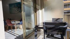 A balcony with a glass door, a table, and two chairs. - Branly 2,2 bedrooms and 1 parking (Cannes)