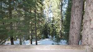A wooden deck with a view of a forested area and a road in the distance.