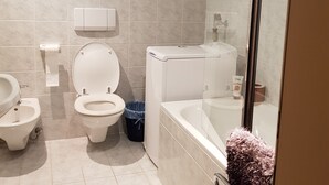 Een moderne badkamer met twee toiletten, een bidet, een bad en een douchecabine met glazen wanden.