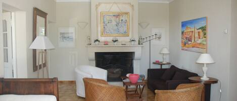 A living room with a fireplace, wicker furniture, and artwork on the walls.