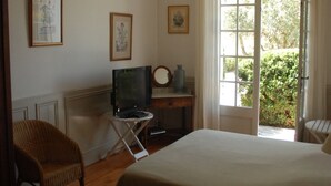 A bedroom with a large bed, a television on a stand, a chair, and a small table. - Provence ideally located in the middle of vineyards, single storey villa 8 pers. (Gigondas)