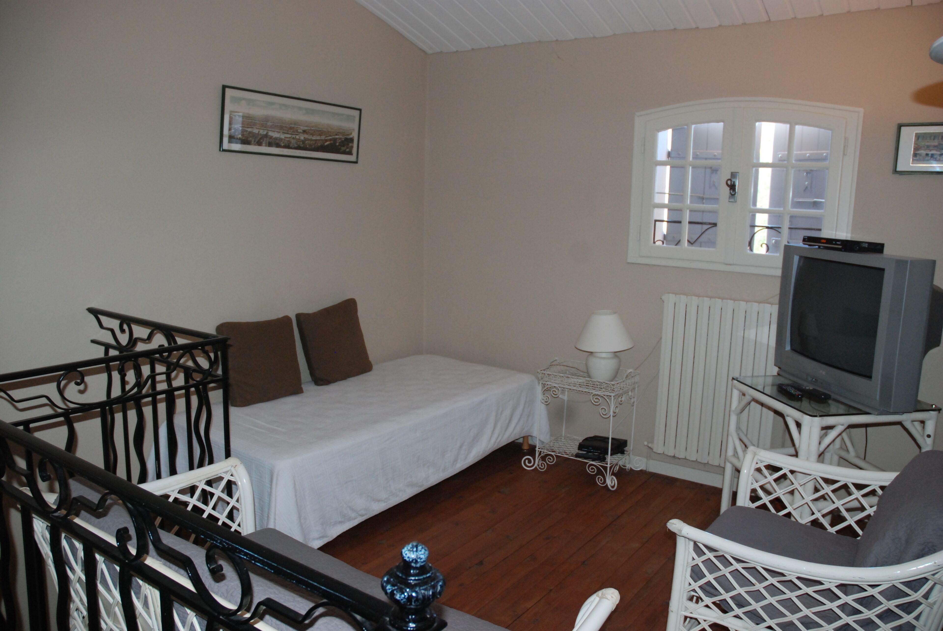 Ein kleines, gemütliches Zimmer mit Bett, Fernseher, Lampe und Fenster.