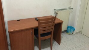 A wooden desk with a chair, a radiator, and a trash bin. - Les Artes (Rome)