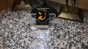A lamp with a white lampshade on a granite countertop, flanked by two golden statues. - Les Artes (Rome)