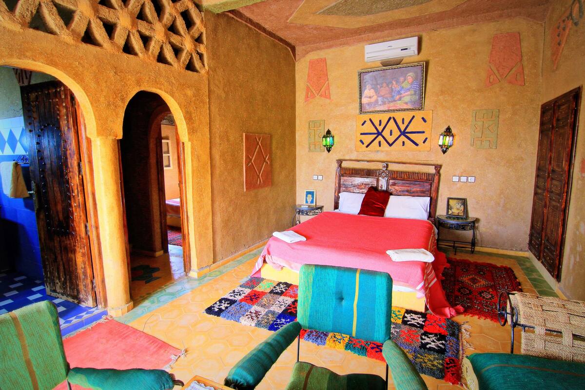 Una habitación tradicional con cama, alfombras coloridas y una puerta de madera.