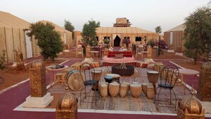 A desert-style courtyard with seating areas, a central fire pit, and decorative lanterns. - Dar Tafouyte (Taouz)