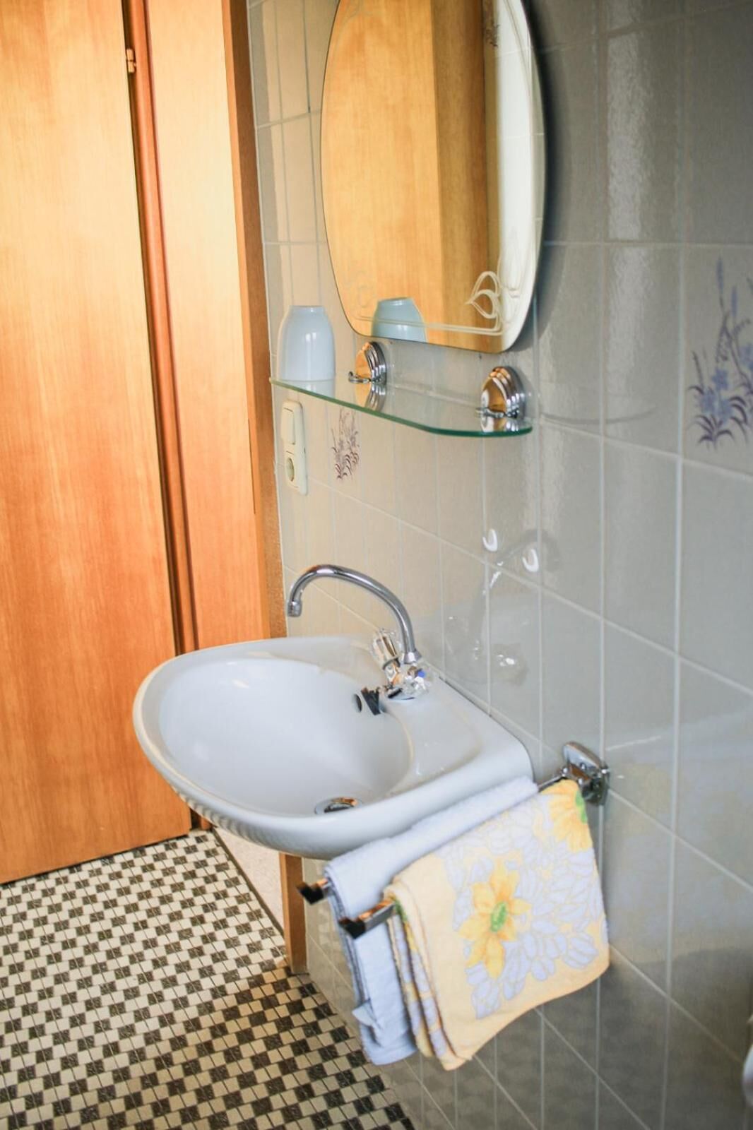 Un baño con lavamanos, espejo y toallero.