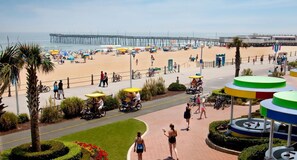 Un paseo marítimo con un muelle al fondo, zona de alquiler de bicicletas y un jardín circular.