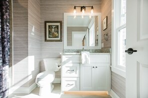 Une salle de bain avec des toilettes, un meuble-lavabo et un grand miroir.