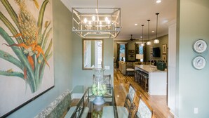 A dining area with a glass table, chairs, a chandelier, and a large botanical painting on the wall. - Plunge Pool and Parking, 3 Stories in Historic Downtown by Lucky Savannah (Savannah)
