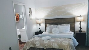 A neatly arranged hotel room with a large bed, two bedside lamps, a headboard, and a view of the hallway. - Quiet Townhome in central Raleigh (Raleigh)