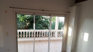 Et værelse med en skydedør, der fører ud til en balkon med et hvidt gelænder.