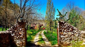 A stone gate leading into a path surrounded by trees and greenery. - A magical house in the heart of Guadarrama Park (Collado Hermoso)