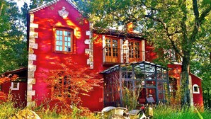 A red two-story house with a balcony and a bicycle parked in front. - A magical house in the heart of Guadarrama Park (Collado Hermoso)