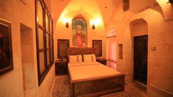 A traditional room with a wooden bed, a religious painting, and a patterned rug.