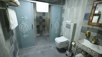 A bathroom with a toilet, sink, and glass shower enclosure.
