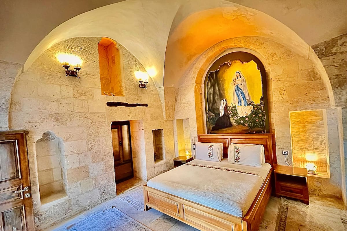 Ein Schlafzimmer mit einem großen Bett, Steinwänden und einem religiösen Gemälde über dem Bett.