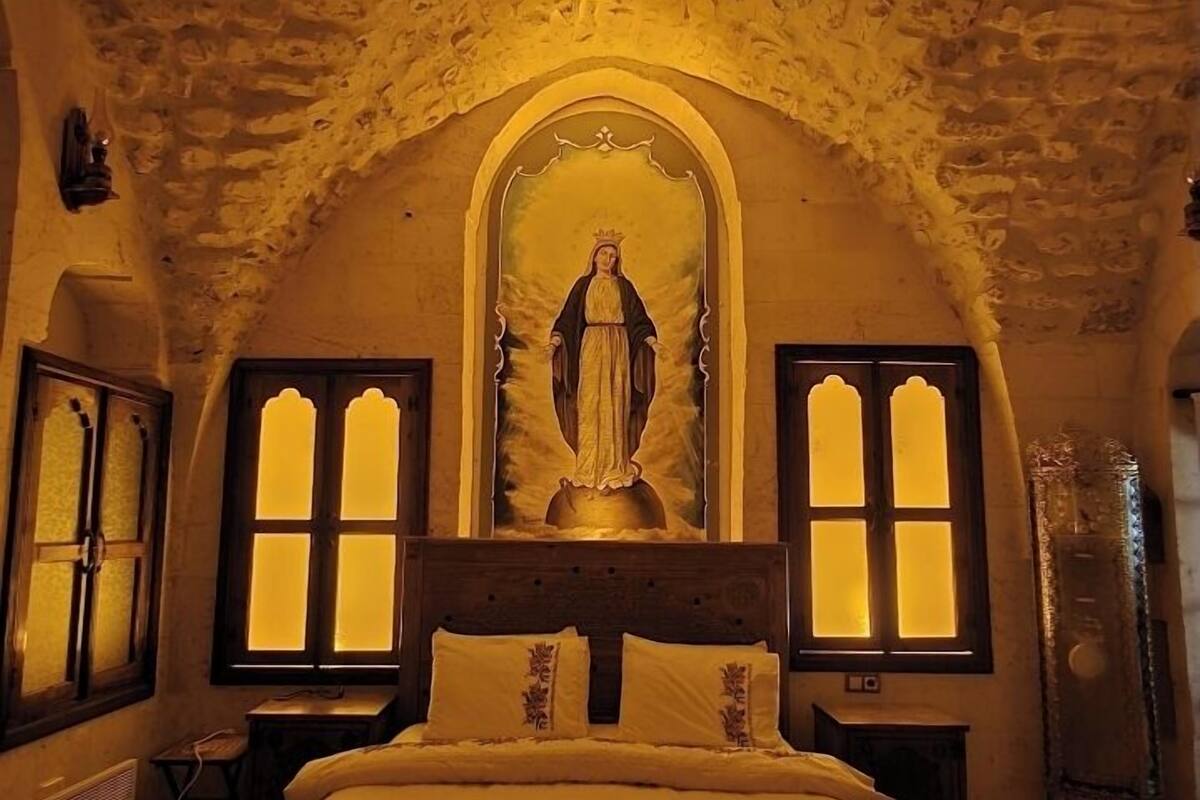 Ein Zimmer mit einem Bett, einer an der Wand befestigten religiösen Ikone und zwei Fenstern mit beleuchteten Panels.