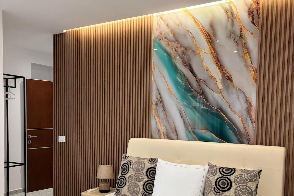 A modern bedroom with a large bed, a marble wall, and a wooden panel design.