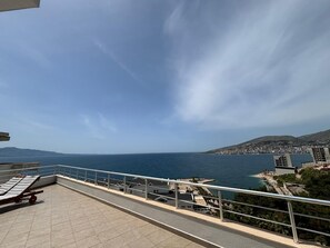 A terrace with a view of the sea and a distant cityscape. - Bella Vista Hotel (Sarandë)