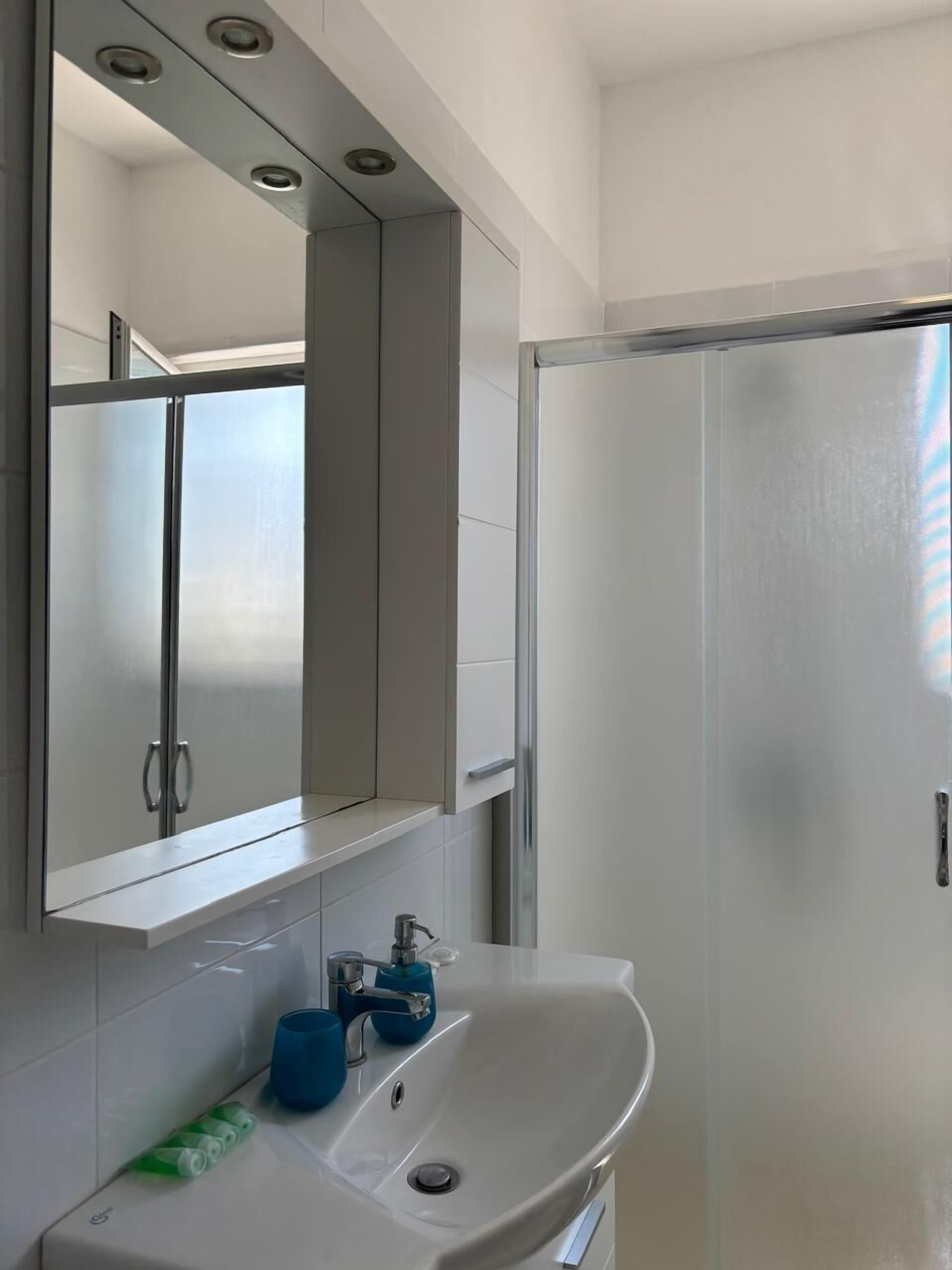 A modern bathroom with a large mirror, a sink, and a shower area.