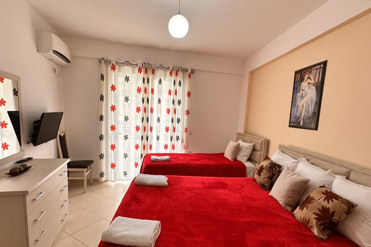 A hotel room with two beds, a desk with a computer, a TV, and a painting on the wall.