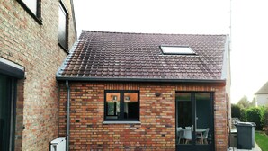 Une petite maison en briques avec un toit en tuiles, une porte-fenêtre coulissante et une petite fenêtre.