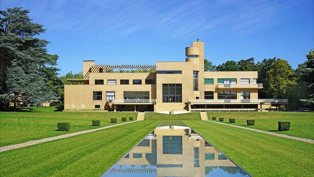 Un bâtiment moderne doté d’une cour intérieure et d’un élément décoratif aquatique aux reflets changeants.