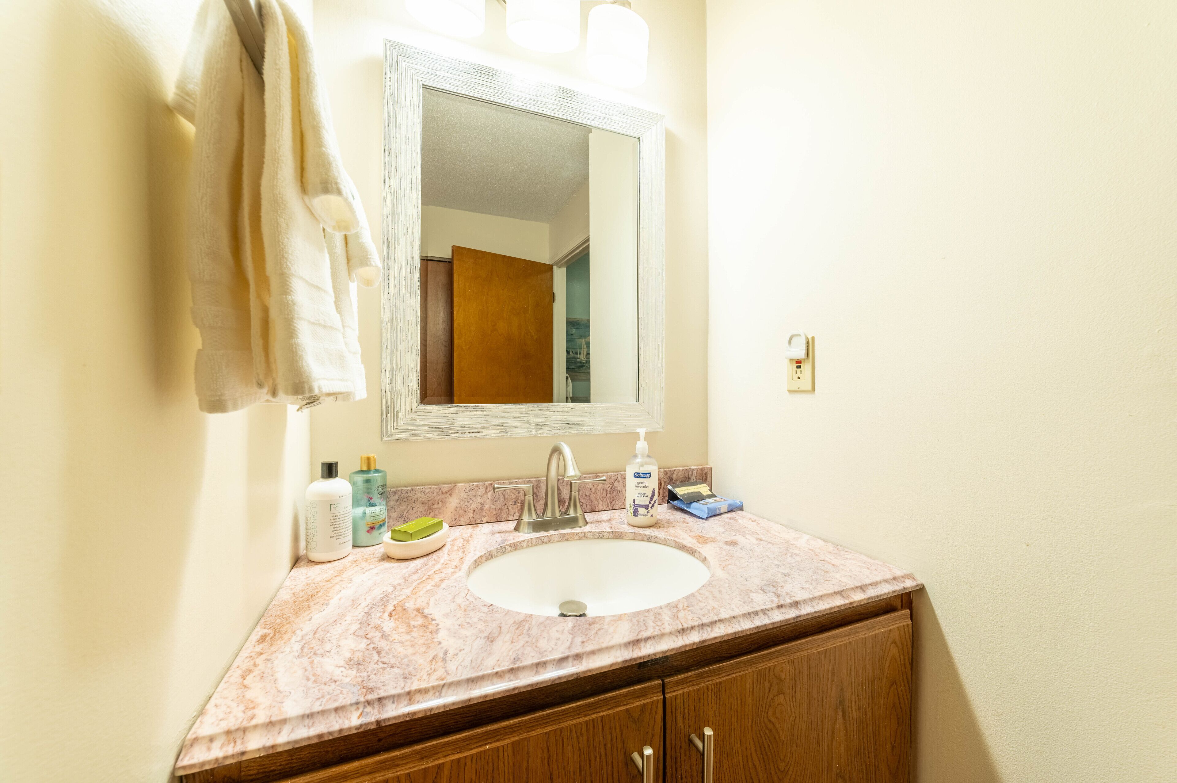 A bathroom with a marble sink, a mirror, and toiletries on the countertop.