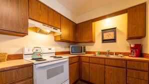 A kitchen with wooden cabinets, a white stove, a microwave, and a red coffee maker. - Hidden Gem in Walloon Village (Walloon Lake)