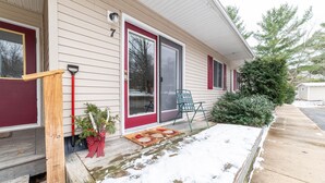 A single-story house with a front porch, a red door, and a green chair outside. - Hidden Gem in Walloon Village (Walloon Lake)