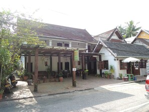 A traditional building with a covered veranda, potted plants, and a small outdoor seating area. - Mani Home & Hostel Luang Prabang (Luang Prabang)