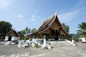 A traditional temple with a multi-tiered roof, ornate decorations, and a central statue. - Mani Home & Hostel Luang Prabang (Luang Prabang)