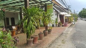 A covered outdoor seating area with potted plants and a sign for 'Mami Home'.